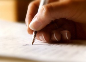 Close-up photo of a hand holding a pen and writing on paper